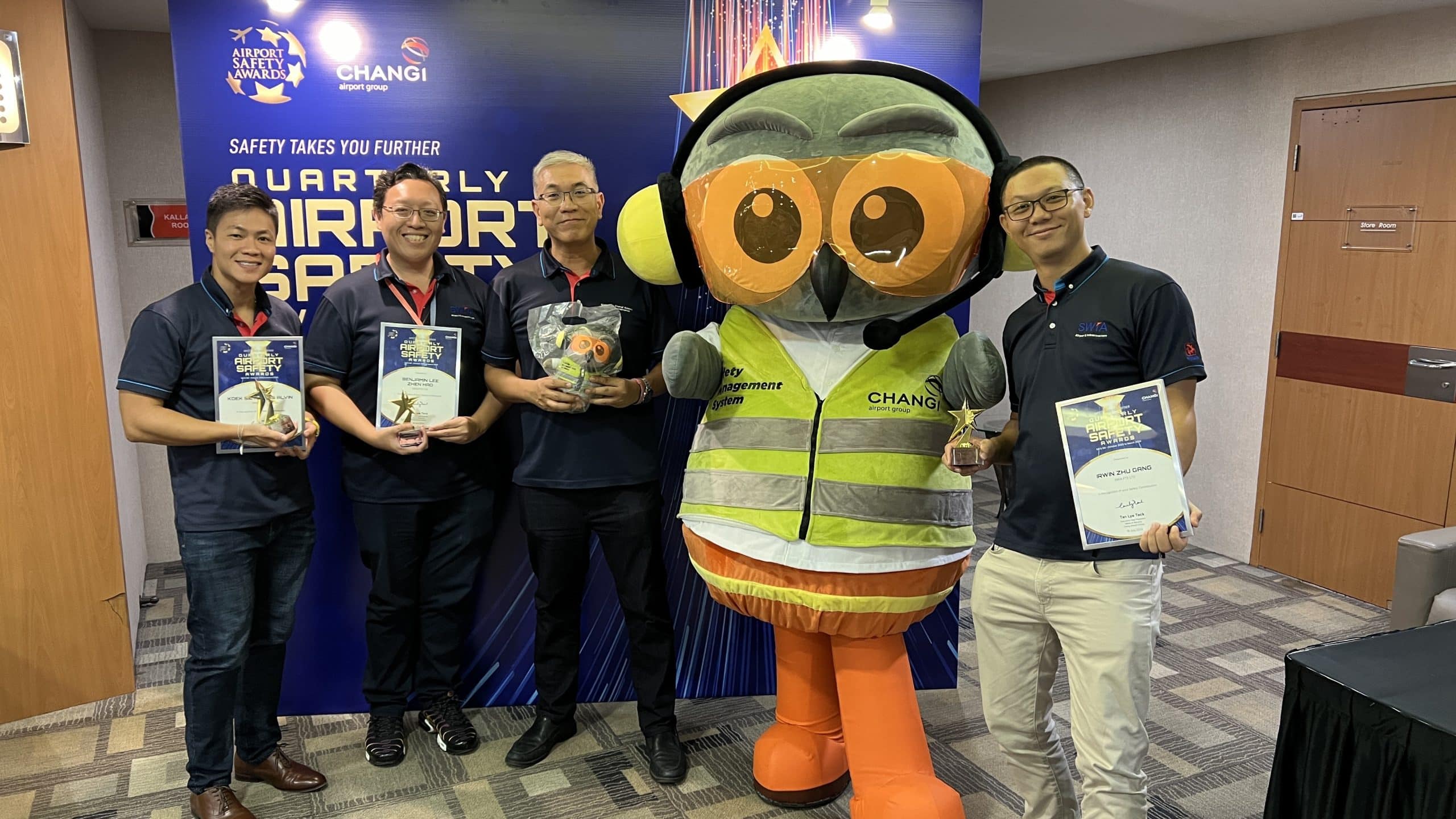 Members of the Samwoh Airport and Infrastructure team proudly holding the Changi Airport Group Quarterly Safety Awards trophy, smiling and celebrating their achievement at a formal event.